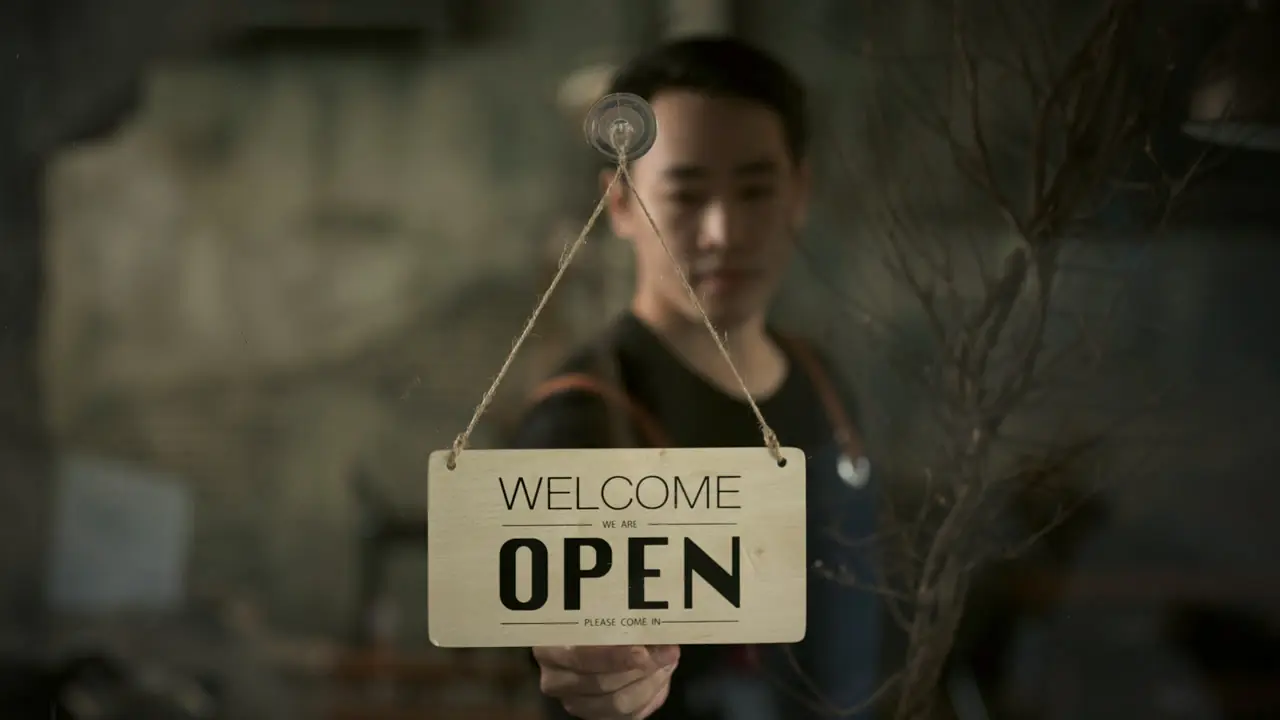A shop owner turning the sign to Open